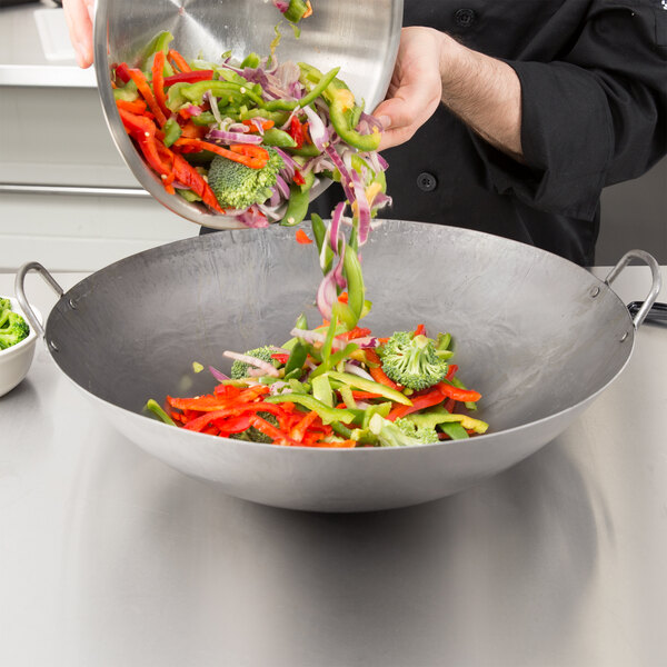 A chef using a Town hand hammered Cantonese wok to cook vegetables.