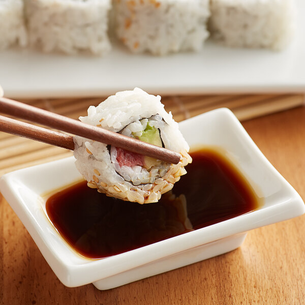 someone dipping sushi in tamari sauce