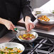 A person using a Choice silicone pan handle cover on a frying pan to cook potatoes with herbs.